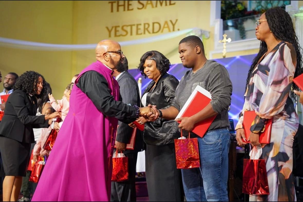 Bishop Hilliard, in purple vestments, greeting members of the congregation at Cathedral International